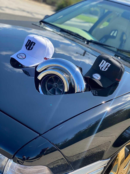black vl turbo a-frame snapback cap and white vl turbo a-frame snapback cap on the bonnet of a holden commodore vl turbo with large turbo
