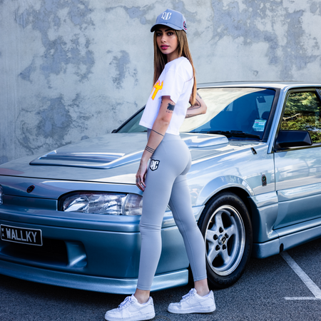 attractive young female model wearing racecraft gray legging tights in front of vl walkinshaw car